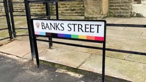 A Banks Street sign in Blackpool with a Progress Pride stripe along the bottom